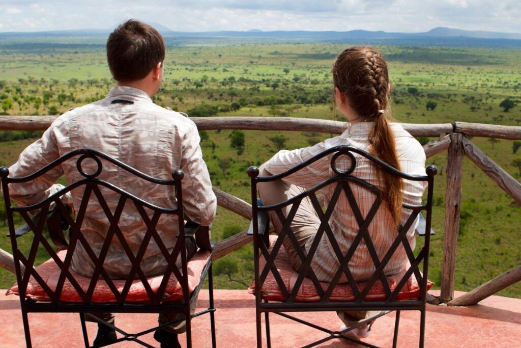 Couple enjoying a breathtaking safari view of the African savannah from a lodge or lookout point